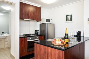 a kitchen with a refrigerator and a table with a bowl of fruit at Melbourne CBD Apt With A C Balcony & Pool in Melbourne