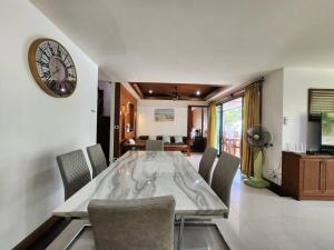 a dining room with a table and a clock on the wall at D30长住优惠-市中心海边高端别墅区6间卧室泳池别墅 in Pattaya Central