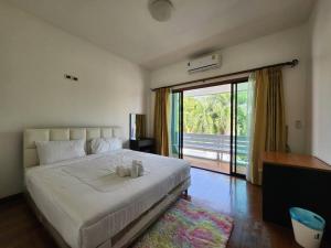 a bedroom with a large white bed with a balcony at D30长住优惠-市中心海边高端别墅区6间卧室泳池别墅 in Pattaya Central +8 photos