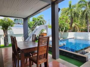 a dining area with a table and chairs and a swimming pool at D30长住优惠-市中心海边高端别墅区6间卧室泳池别墅 in Pattaya Central
