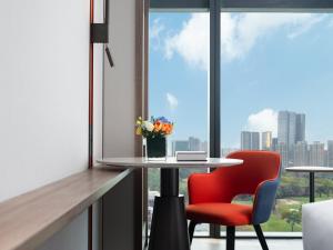 einen Tisch und einen roten Stuhl in einem Zimmer mit Fenster in der Unterkunft Holiday Inn Express Shenzhen Futian Center, an IHG Hotel in Shenzhen