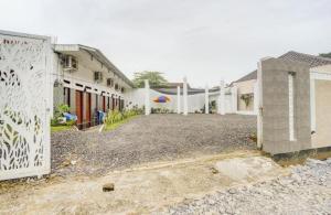 Oemah Ratu Hostel Syariah RedPartner في بندر لامبونغ: مجموعة من المباني البيضاء مع ساحة حصى