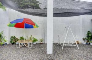 eine Terrasse mit einem Tisch, einem bunten Sonnenschirm und Stühlen in der Unterkunft Oemah Ratu Hostel Syariah RedPartner in Bandar Lampung