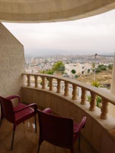 a balcony with chairs and a view of a city at Lotus housing for furnished apartments in Jerash