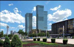 Deux grands bâtiments dans une ville avec un parking dans l'établissement Северное Сияние 41 этаж 01, à Astana