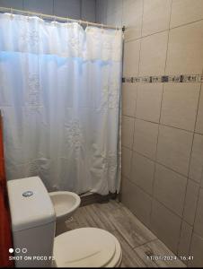 a bathroom with a toilet and a white shower curtain at Alquimia Qi del Mar in Mar de Cobo +46 photos