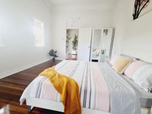 Un dormitorio blanco con una cama con una manta amarilla. en Exclusive location - Entire 3-bedroom in Maryborough CBD, 10ppl, en Maryborough