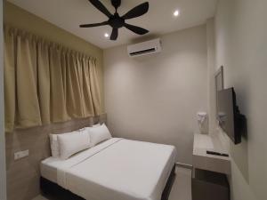 een slaapkamer met een wit bed en een plafondventilator bij Eighteen Guesthouse in Kuantan