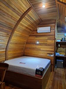 a bed in a room with a wooden wall at Seaview Eagles Nest Cabins in Rawai Beach