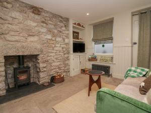 a living room with a stone wall with a fireplace at Gosling Cottage in Kendal