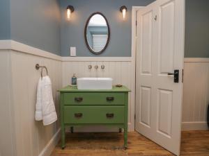 a bathroom with a green sink and a mirror at Gosling Cottage in Kendal