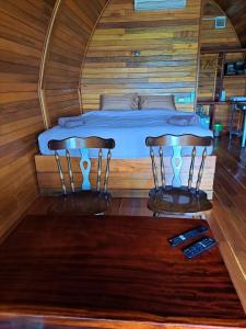 Cama en habitación de madera con 2 sillas en Seaview Eagles Nest Cabins en Rawai Beach