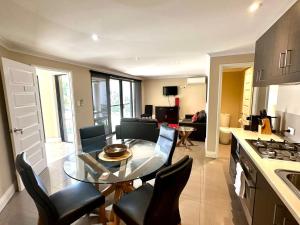 a kitchen and living room with a glass table and chairs at Ocean View Executive Apartment 1 in Busselton