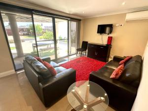 a living room with two leather couches and a television at Ocean View Executive Apartment 1 in Busselton