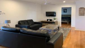 a living room with two leather couches and a television at Boat Ramp Shack in Coffin Bay