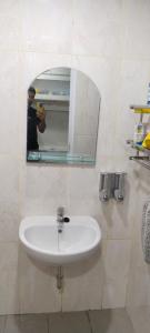 un hombre tomando una foto de un lavabo en un baño en Apartermen Skylouge Makassar en Manda