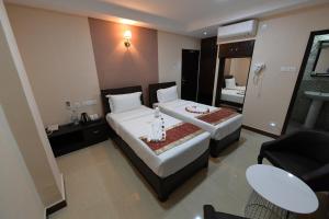 a hotel room with two beds and a bathroom at Coastal Grand Hotel Sampath in Tiruchchirāppalli