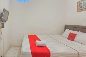 - une chambre dotée d'un lit avec une couverture rouge et blanche dans l'établissement RedDoorz near Alun Alun Cianjur, à Cianjur