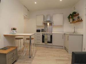 a kitchen with white cabinets and a table and stools at Basement Flat 43 in Keighley