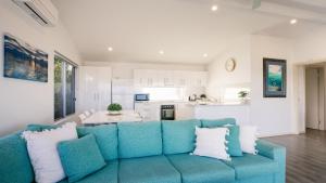 a living room with a blue couch and a kitchen at Beachside in Coffin Bay