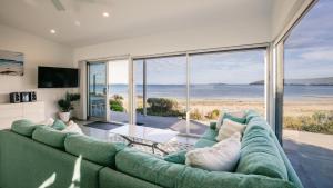 een woonkamer met een groene bank en uitzicht op de oceaan bij Beachside in Coffin Bay