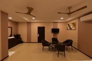 Pokój ze stołem, krzesłami i telewizorem w obiekcie Coastal Grand Hotel Sampath w mieście Tiruchchirāppalli