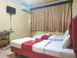 Duas camas num quarto com uma secretária e uma janela em RedDoorz Syariah At Hotel Matahari 1 Jambi em Jambi