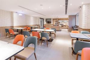 a restaurant with tables and chairs and a kitchen at Hanting Hotel Anshan Women and Children Hospital in Anshan