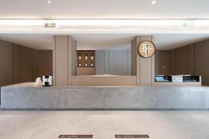 a lobby with a counter with a clock on the wall at Ji Hotel Yantai Guanhai Road Fisherman's Wharf in Qianqikuang
