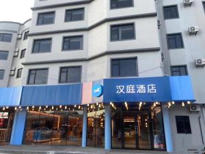 un edificio con una señal azul delante de él en Hanting Hotel Haikou East Railway Station Zhanqian Square en Pin-lien