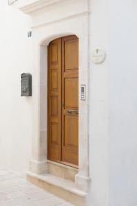 una porta di legno sul lato di un edificio bianco di Lapignagialla a Martina Franca