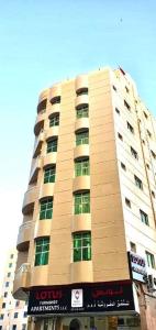 un grand bâtiment avec un panneau devant lui dans l'établissement Lotus Furnished Hotel Apartments LLC. Ajman, à Ajman