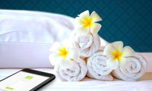 um grupo de toalhas com flores numa cama com um telemóvel em Lotus Furnished Hotel Apartments LLC. Ajman em Ajman