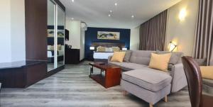 Habitación de hotel con sofá y cama en Grand Aria Hotel, en Gaborone