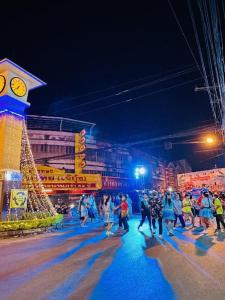 a group of people walking on a street with a clock tower at นิวธาราเพลส หล่มสัก โรงแรม in Ban Nam Phung