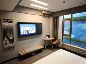 a room with a tv on a wall with a table at Thank Hotel Shanxi Lvliang Zhongyang County North Fengcheng Street in Zhongyang