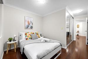 a white bedroom with a bed and a table at 2 Bedrooms Apt in Burwood 4Min To Train Sleep 6 in Sydney