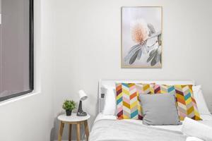 a white bedroom with a bed with a colorful pillow at 2 Bedrooms Apt in Burwood 4Min To Train Sleep 6 in Sydney