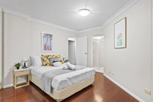 a white bedroom with a large bed in it at 2 Bedrooms Apt in Burwood 4Min To Train Sleep 6 in Sydney