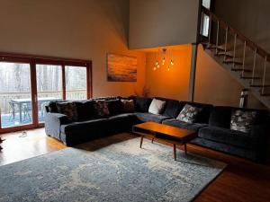 sala de estar con sofá negro y mesa en Pocono Retreat Perfect for Big Family Gatherings, en Long Pond