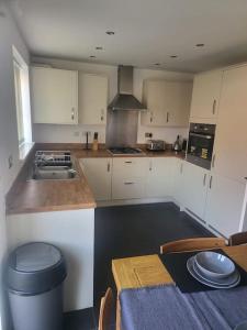 a kitchen with white cabinets and a table and a stove at City Vibes Getaway in Leeds