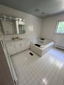 Baño blanco con bañera y lavamanos en Pocono Retreat Perfect for Big Family Gatherings, en Long Pond