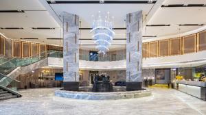 a large lobby with a chandelier in a building at Echarm Hotel Wuzhou Wangcheng Plaza Longmumiao Sanzongfu in Wuzhou