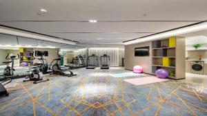 a fitness room with treadmills and exercise equipment at Echarm Hotel Wuzhou Wangcheng Plaza Longmumiao Sanzongfu in Wuzhou