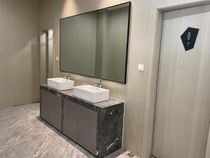 a bathroom with two sinks and a large mirror at Echarm Hotel Wuhu Wanzhi East Lake Yingbin Avenue in Liangzhongchang
