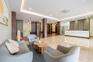 uma sala de estar com duas cadeiras, um sofá e uma mesa em Kio Hotel Korat em Ban Hua La Loeng
