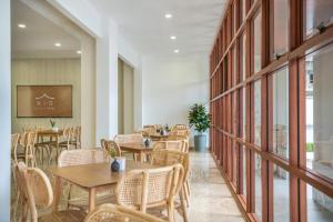 uma sala de jantar com mesas, cadeiras e janelas em Kio Hotel Korat em Ban Hua La Loeng