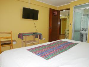 1 dormitorio con 1 cama blanca y TV en la pared en Wayra Hotel, en Huaraz