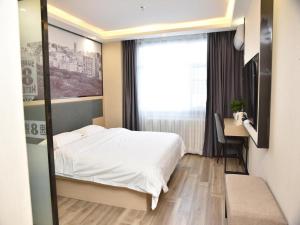 a bedroom with a bed and a desk and a window at Super 8 Hotel Urumqi West Wuyi Road in Ürümqi