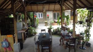 un hombre sentado en una mesa en un pabellón con plantas en Manuh Guest House, en Nusa Dua